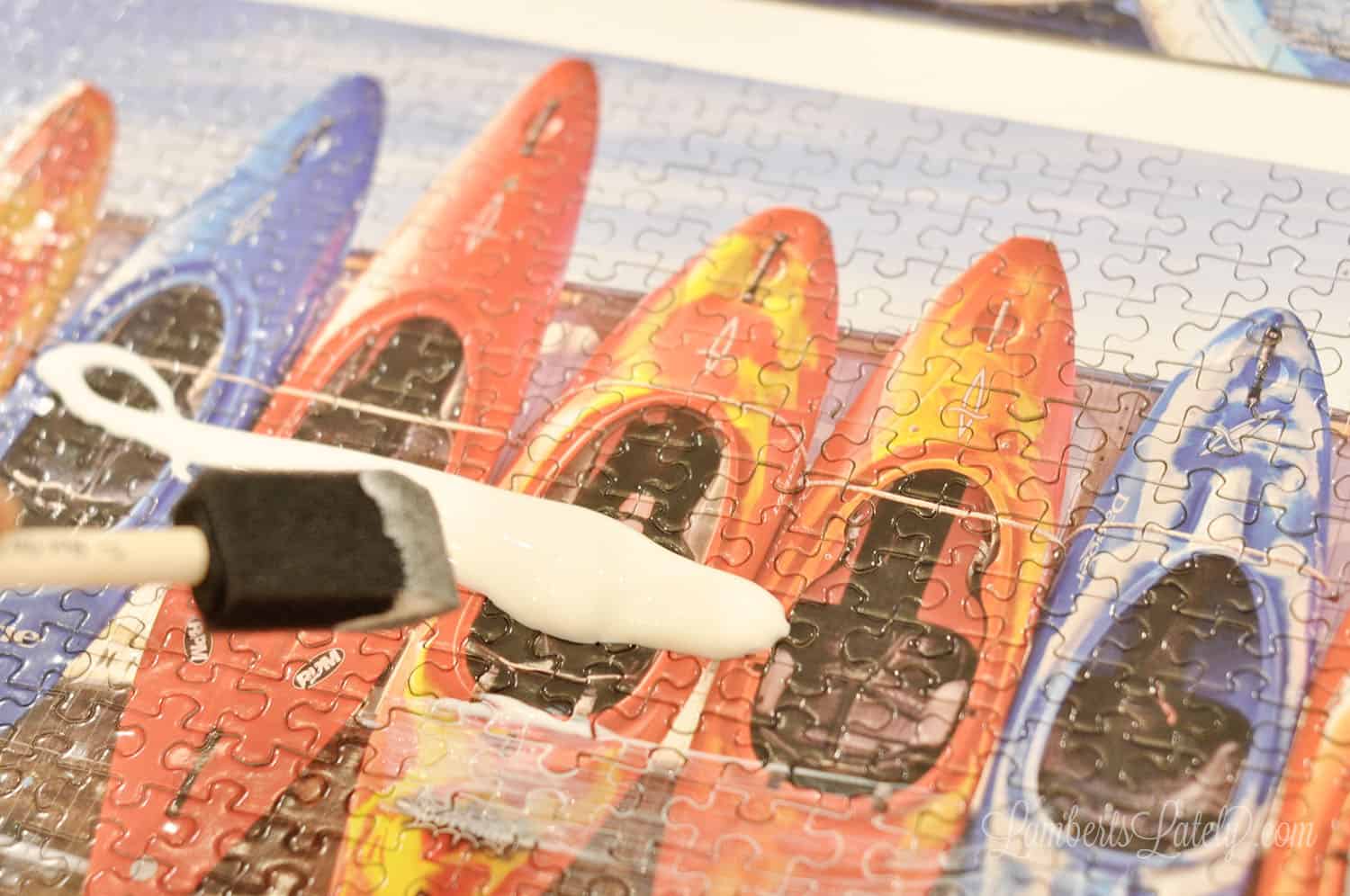 mod podge poured on a puzzle, spreading with a sponge brush.