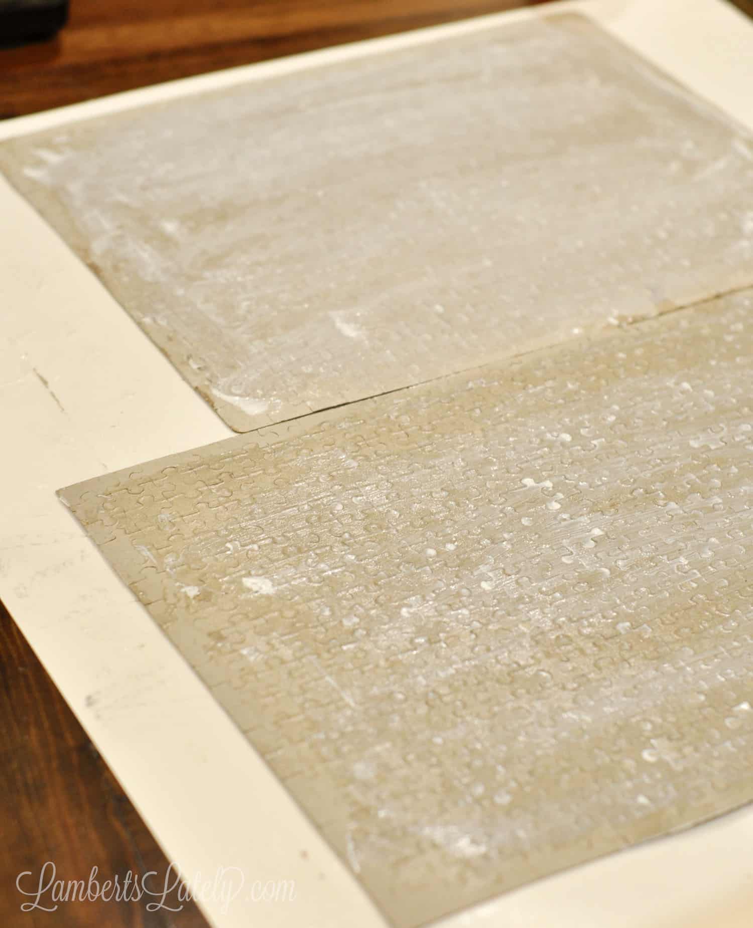 jigsaw puzzles turned over on a piece of poster board, covered in a thin layer of mod podge glue that isn't dried.