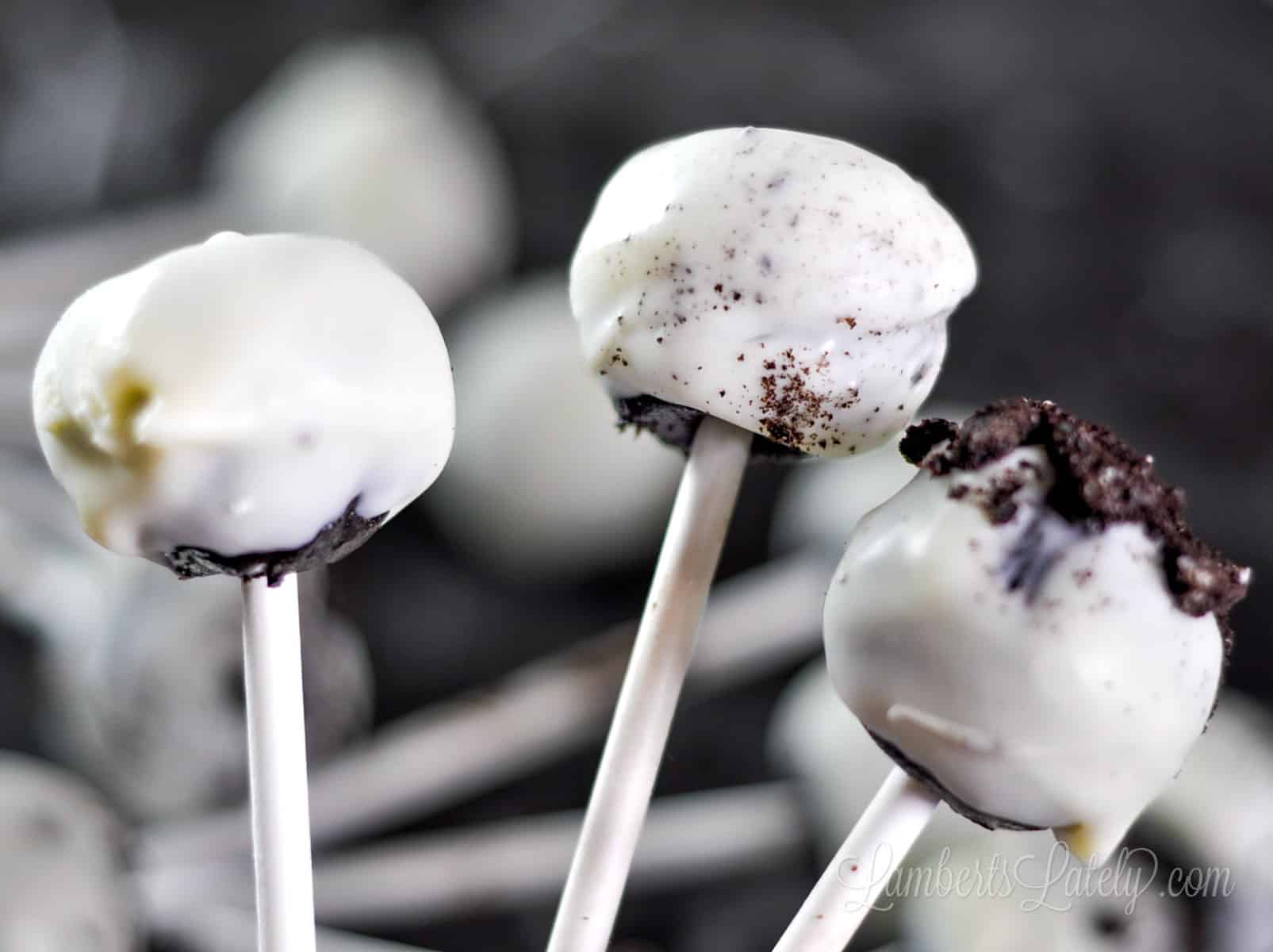 three oreo cake pops in front of a pile of cake pops.