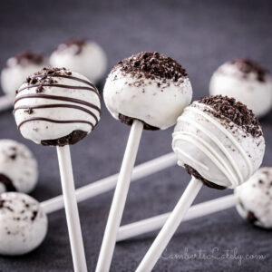 three oreo cake pops in front of a pile of cake pops in the background.