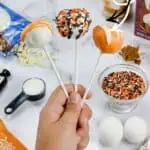 Decorative pumpkin cake pops with sprinkles and themed decorations for fall.