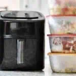Air fryer with meal prep containers for freezer meals on kitchen counter.