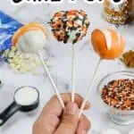 Pumpkin cake pops with orange, black, and white sprinkles on sticks for Halloween.