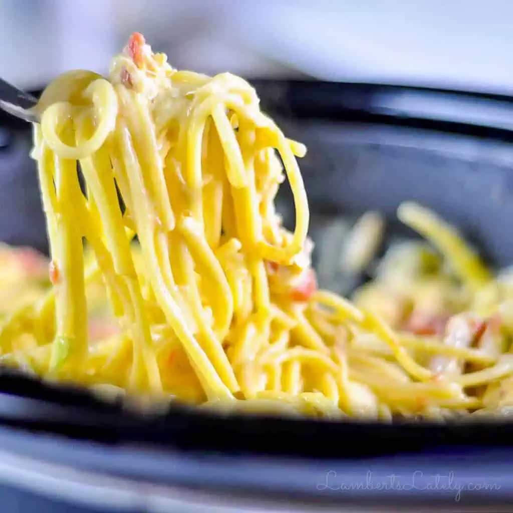 pulling a fork full of chicken spaghetti out of a crock pot.