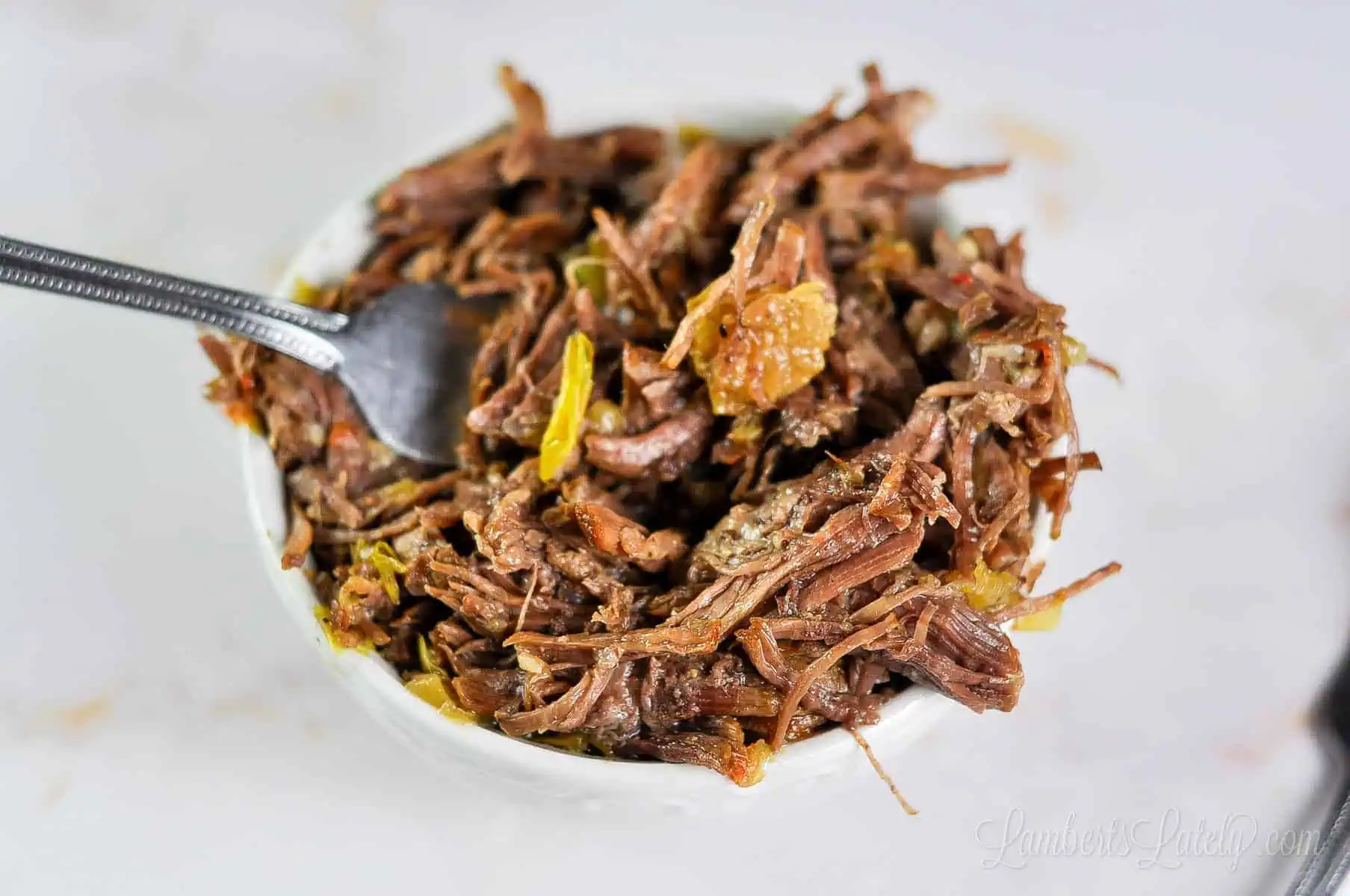 bowl of italian beef with a fork.