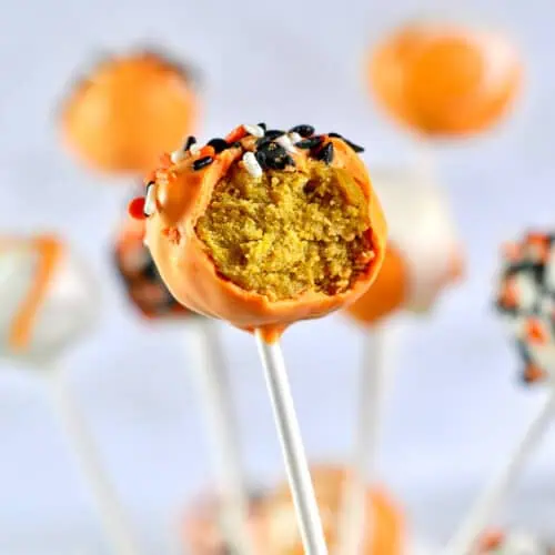 orange pumpkin cake pop missing a bite, showing inside.