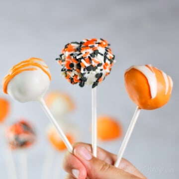 holding three pumpkin cake pops.