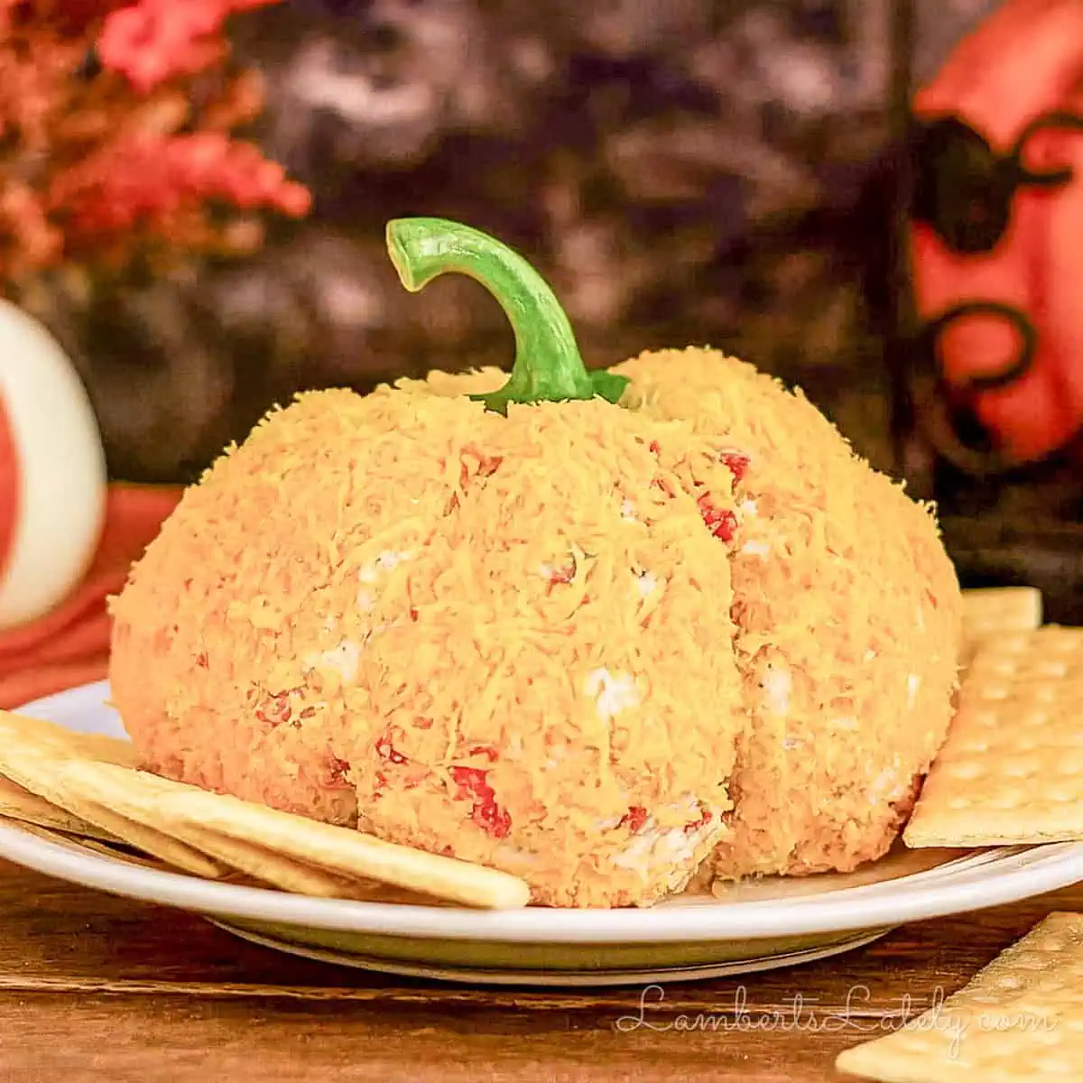 pumpkin cheese ball on a plate surrounded by crackers.