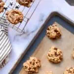 Freshly baked peanut butter chocolate chip cookies on a baking sheet and cooling rack.