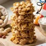 Stack of homemade cornflake no-bake cookies with ingredients and decorations around.