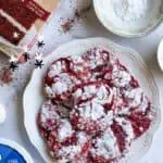 Red velvet cake mix cookies dusted with powdered sugar on a white plate.