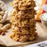 Stack of homemade cornflake no-bake cookies on a wooden surface.