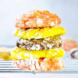 stacked cool whip cake mix cookies (lemon, chocolate, and strawberry) on a baking rack.