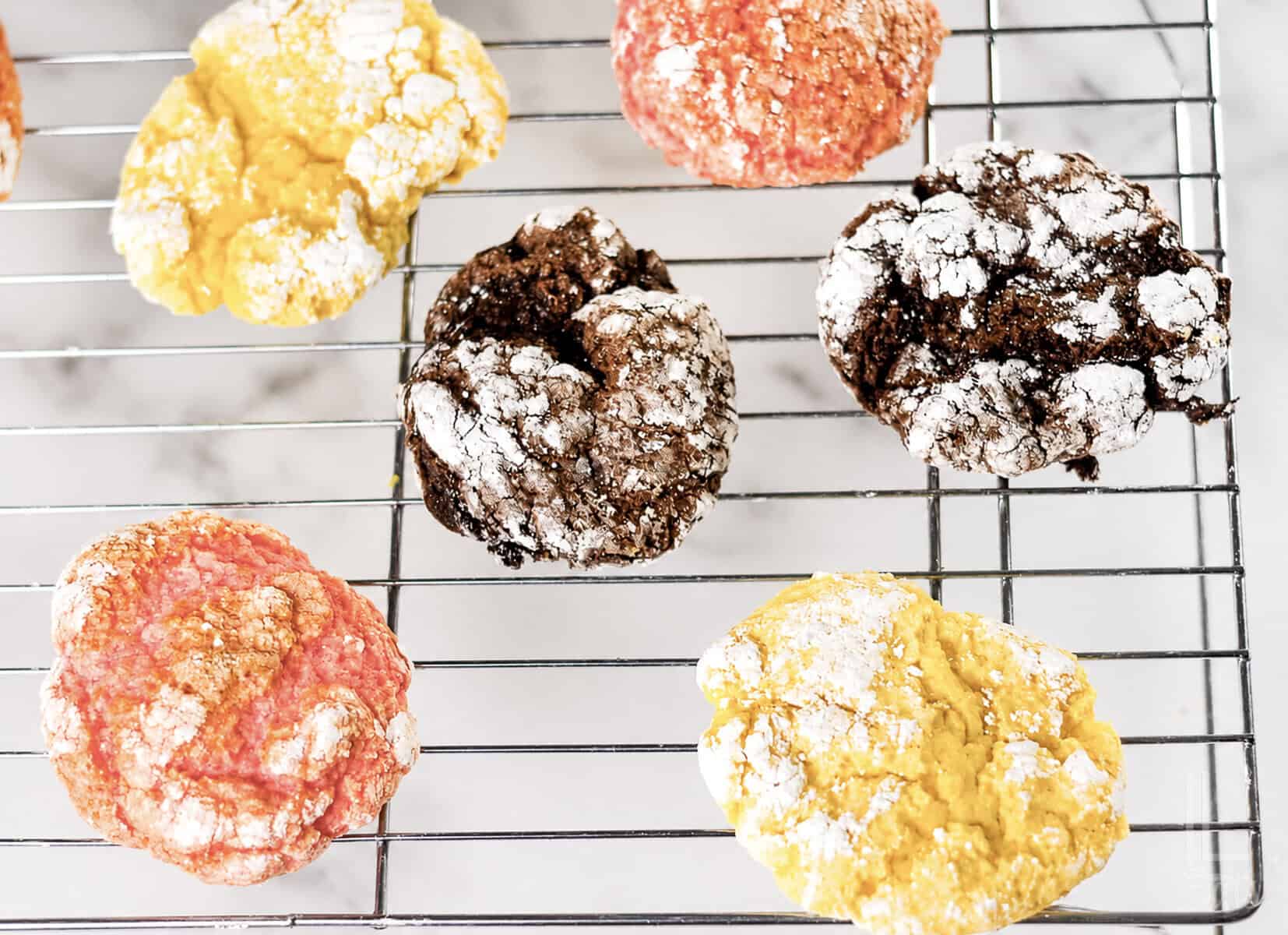 Chocolate, lemon, and strawberry cool whip cake mix cookies on a baking rack.
