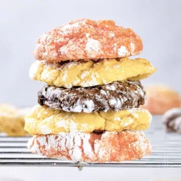 Lemon, chocolate, and strawberry Cool Whip cake mix cookies stacked on a cooling rack.