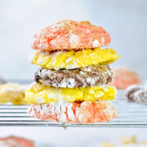 three cool whip cookies (lemon, chocolate, and strawberry) stacked on a wire baking rack.