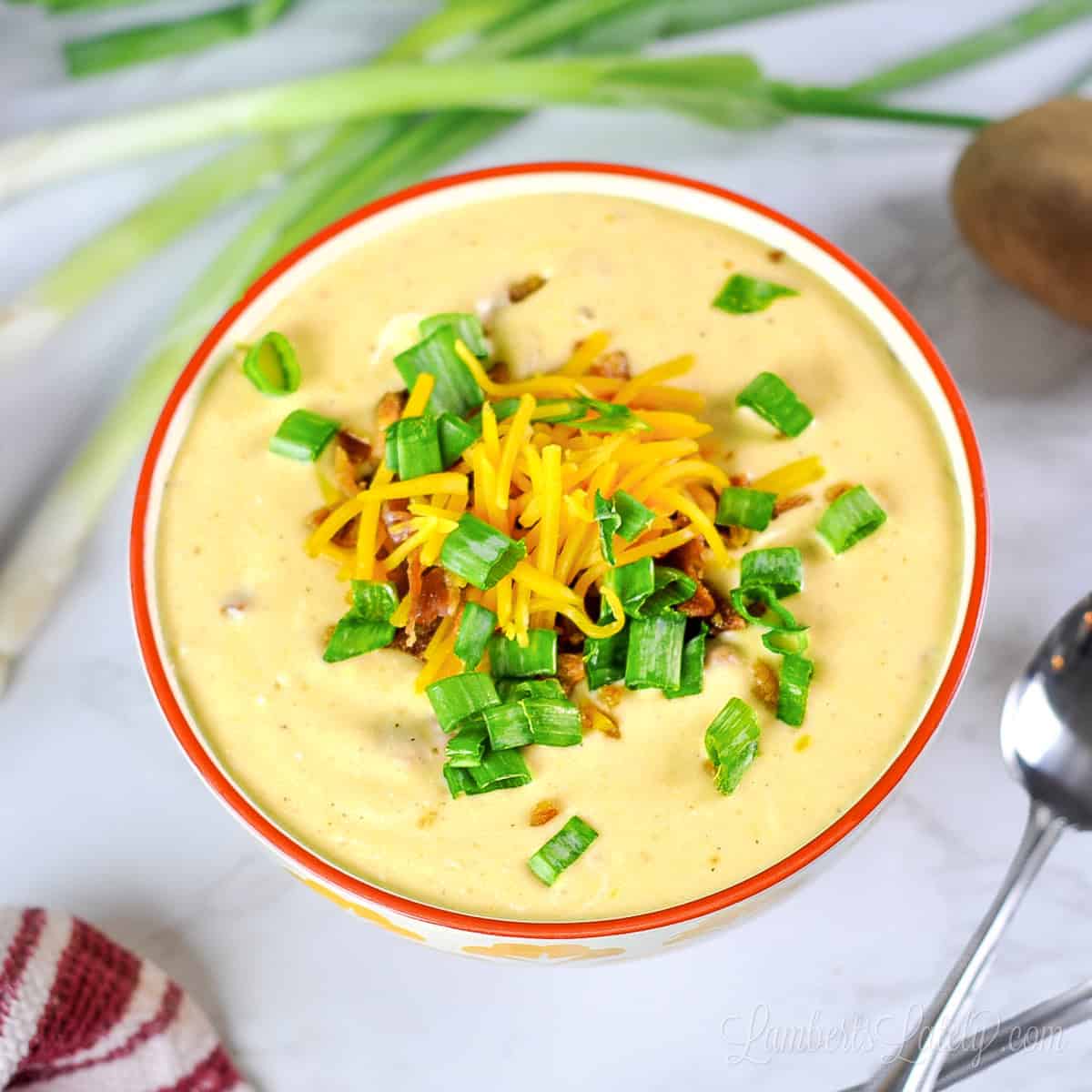 Creamy loaded potato soup topped with shredded cheese and chopped green onions.