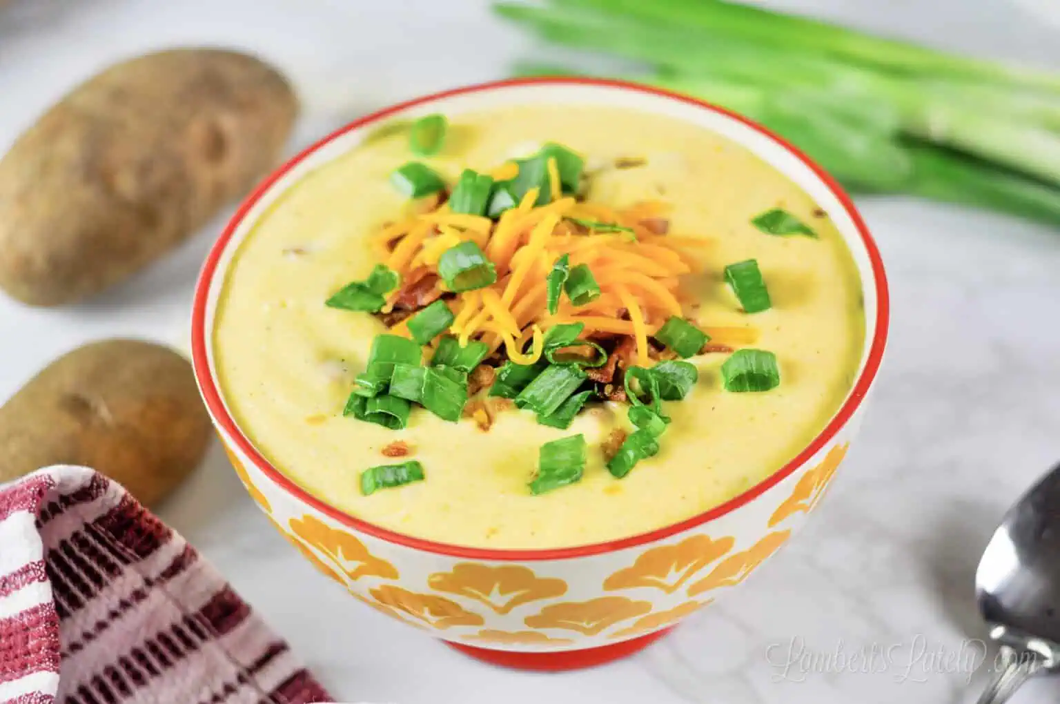 loaded potato soup in a bowl, topped with cheese, green onions, and bacon.