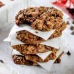 Stack of homemade brownie mix cookies on white paper with milk in background.