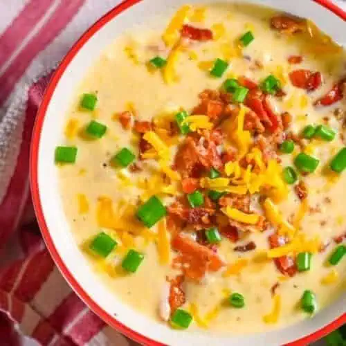 bowl of crockpot corn chowder topped with bacon, cheese, green onions.