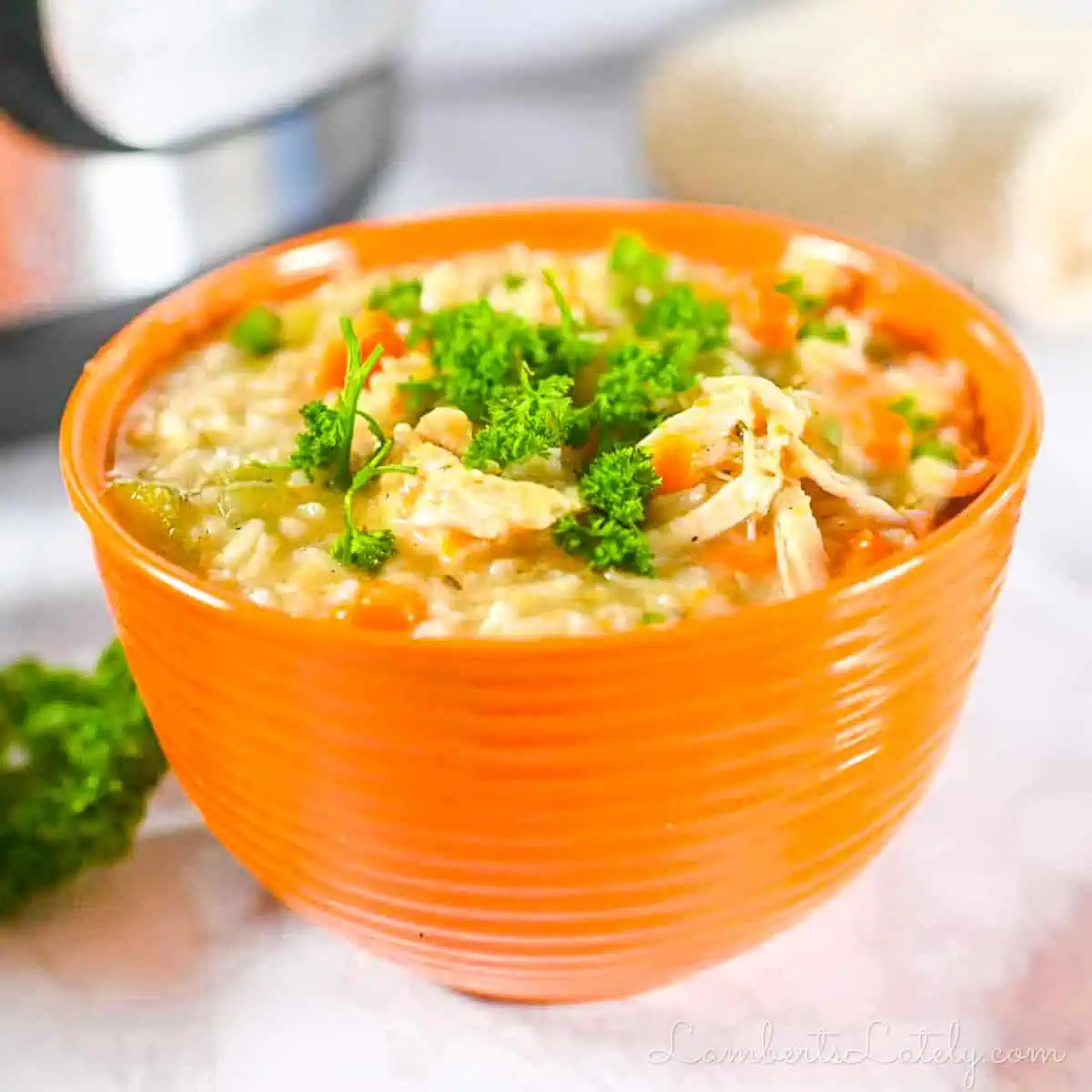 chicken and rice soup in a bow, with a bunch of parsley and an instant pot in the background.