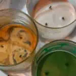 Colorful candles in glass jars with text overlay about cleaning candle jars.