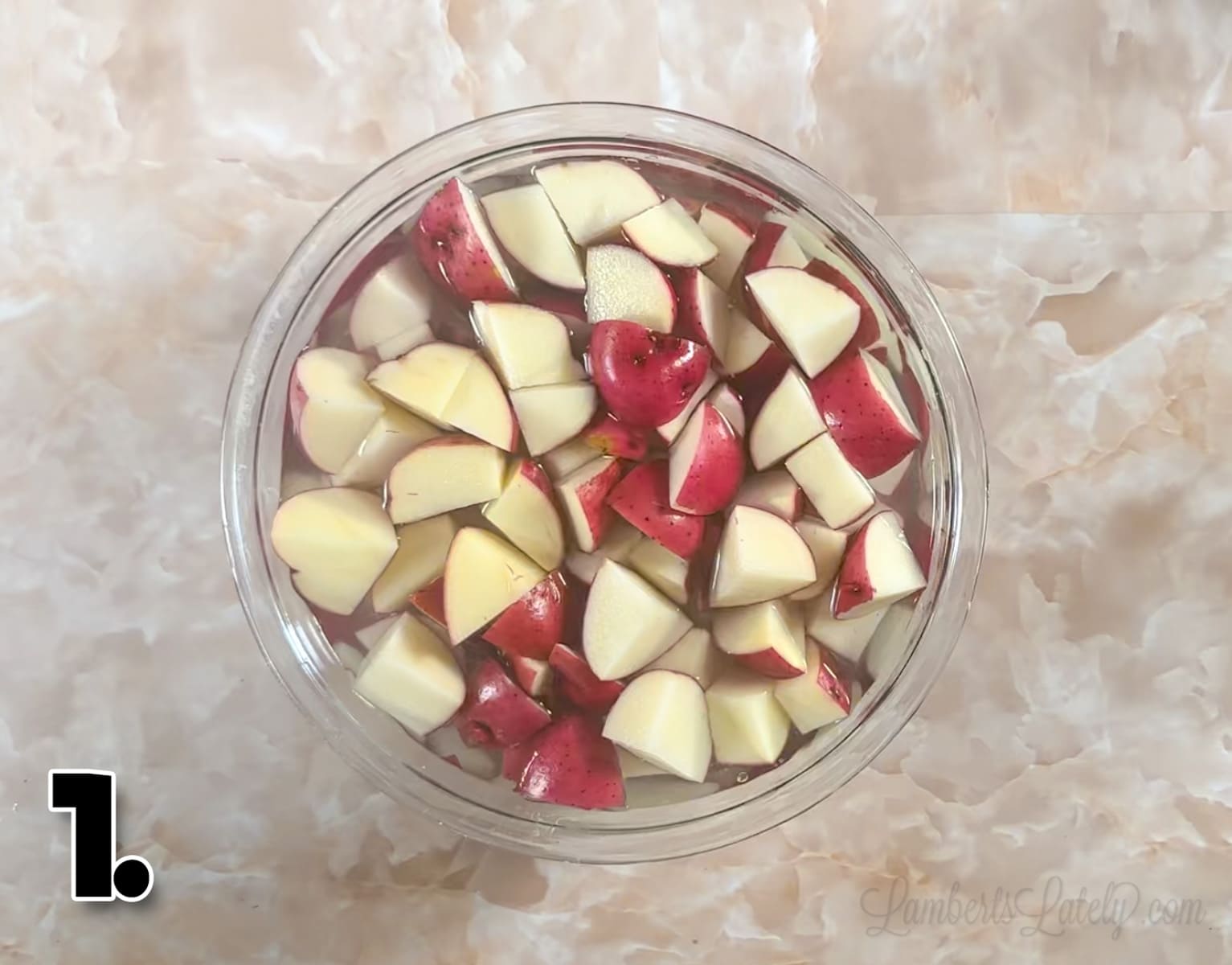 red potatoes, cut into pieces, in a bowl of water.