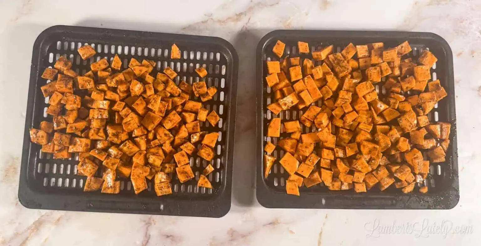 seasoned sweet potato cubes on air fryer trays.