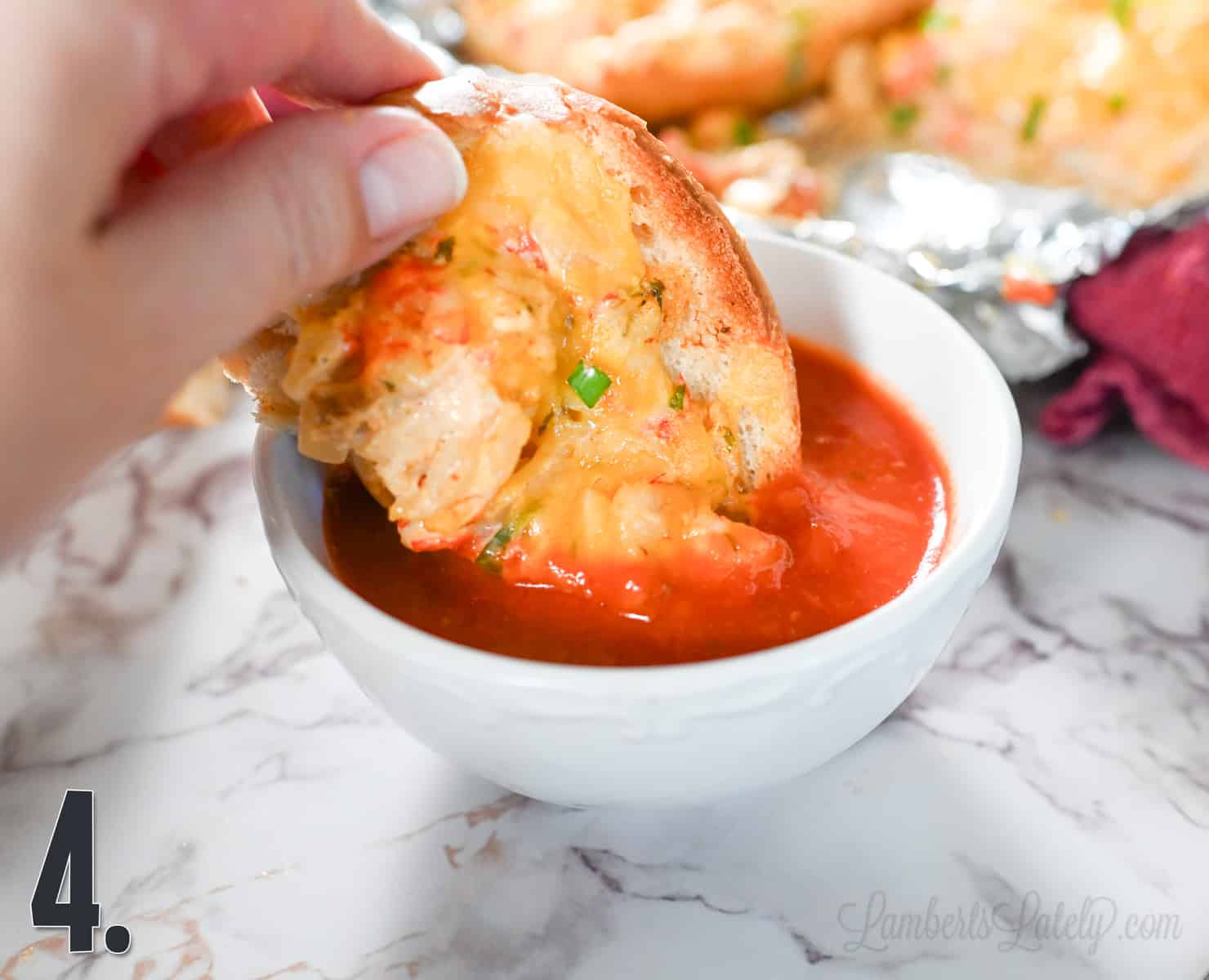 dipping a piece of crawfish bread in marinara sauce.
