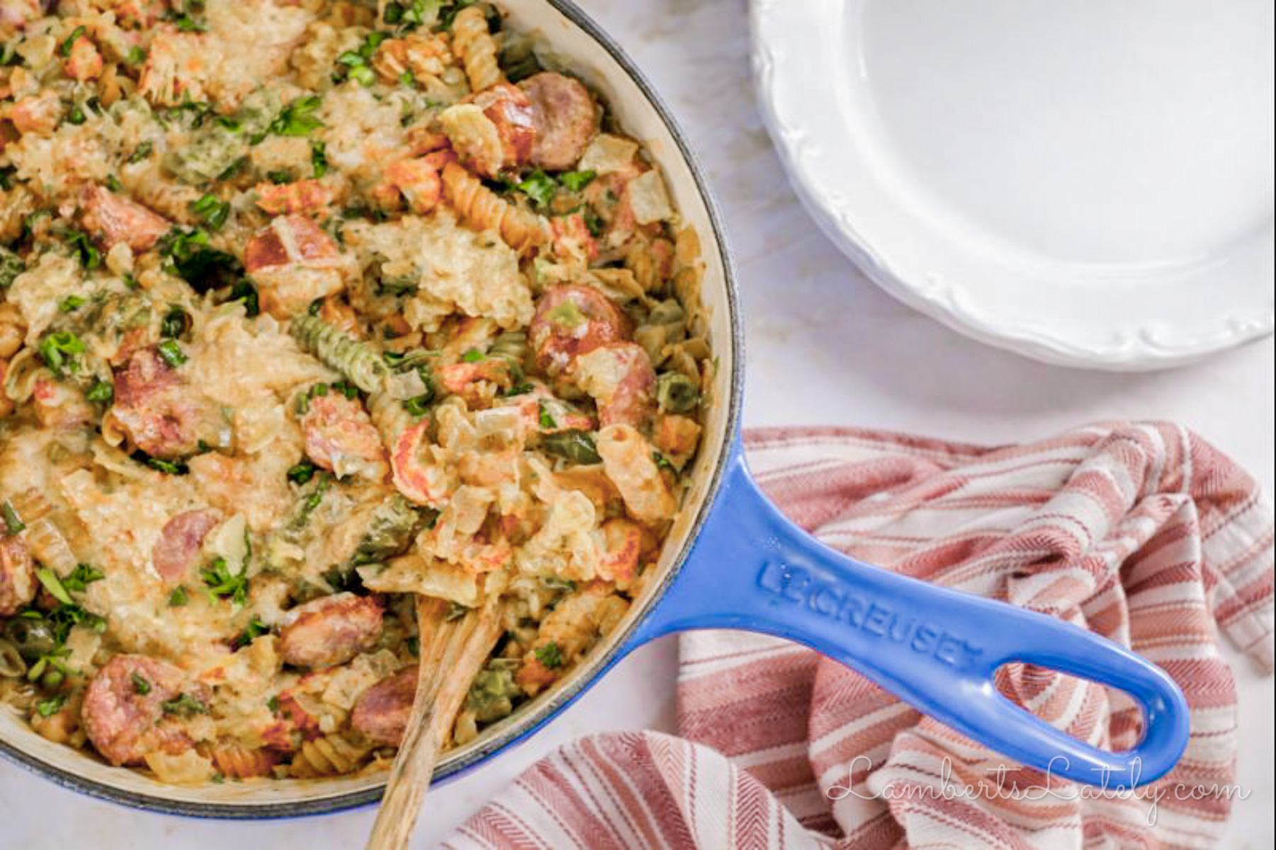 large pot of crawfish monica pasta next to a kitchen towel and plates.
