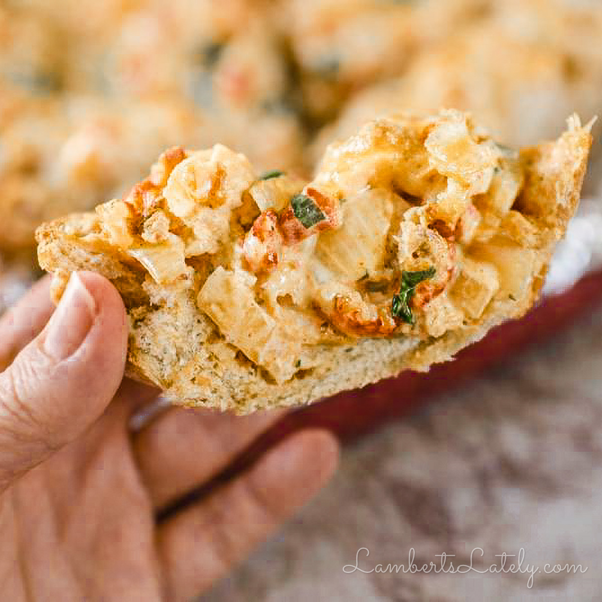 holding a piece of new orleans style crawfish bread, showing crawfish and cheesy sauce.