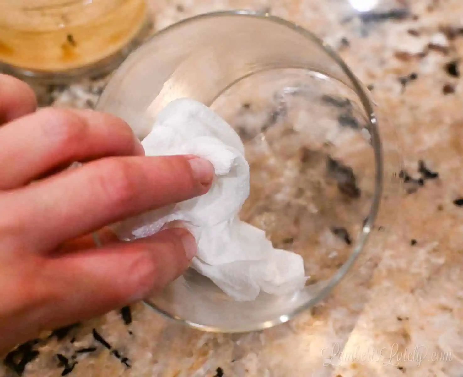 wiping out an empty candle jar with a paper towel.