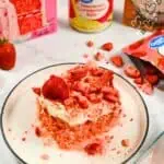 Slice of strawberry tres leches cake with fresh strawberries and cream.