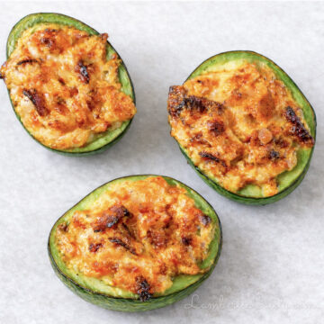 three baked avocado halves, stuffed with bacon and cheese filling.