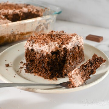 chocolate tres leches cake on a plate with a fork.