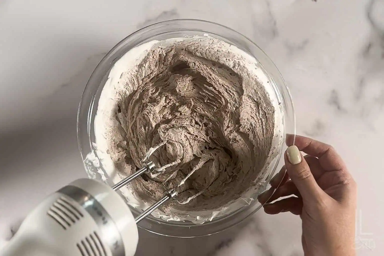Mixing the chocolate whipped cream to top the chocolate tres leches cake.