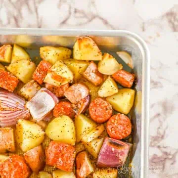 sausage, potatoes, and red onion on a sheet pan.