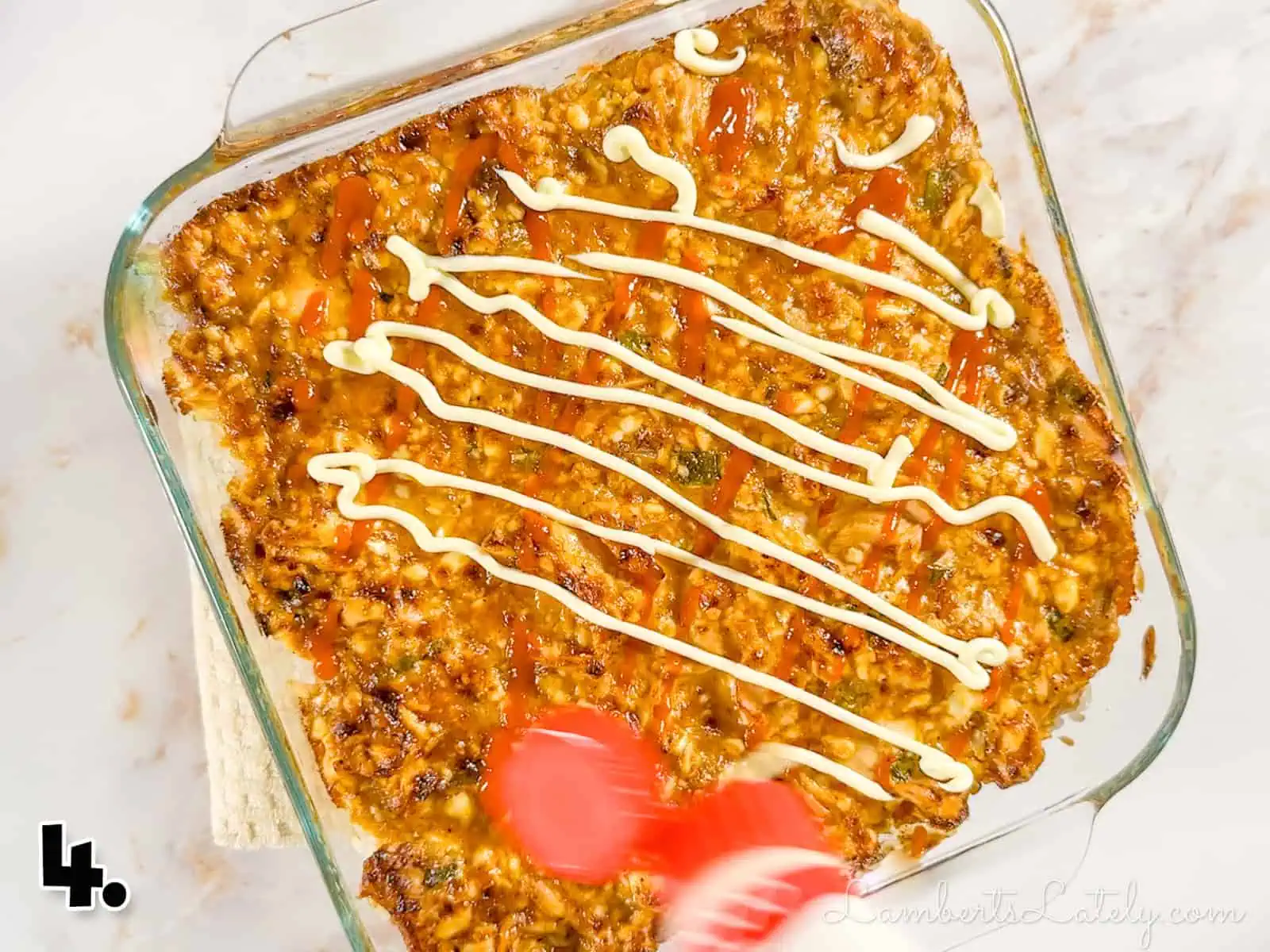 pouring kewpie mayo over baked salmon sushi casserole.