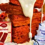 Stack of red velvet waffles with cream cheese glaze and baking ingredients.