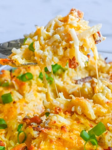 lifting a spoonful of crack potato casserole out of the baking dish.