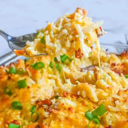 lifting a spoonful of crack potato casserole out of the baking dish.