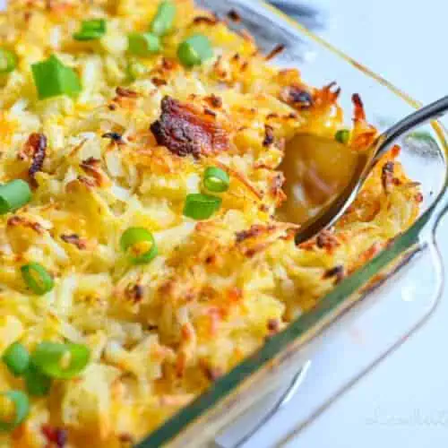 Cheesy baked potato casserole with green onions in a glass dish.