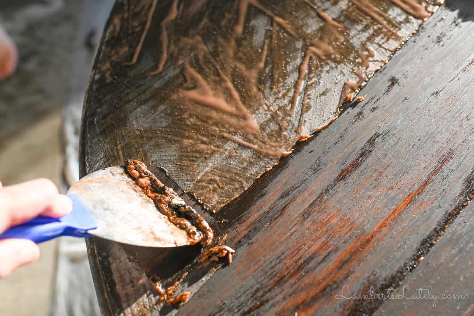 using a paint scraper to take off stripping gel and stain.