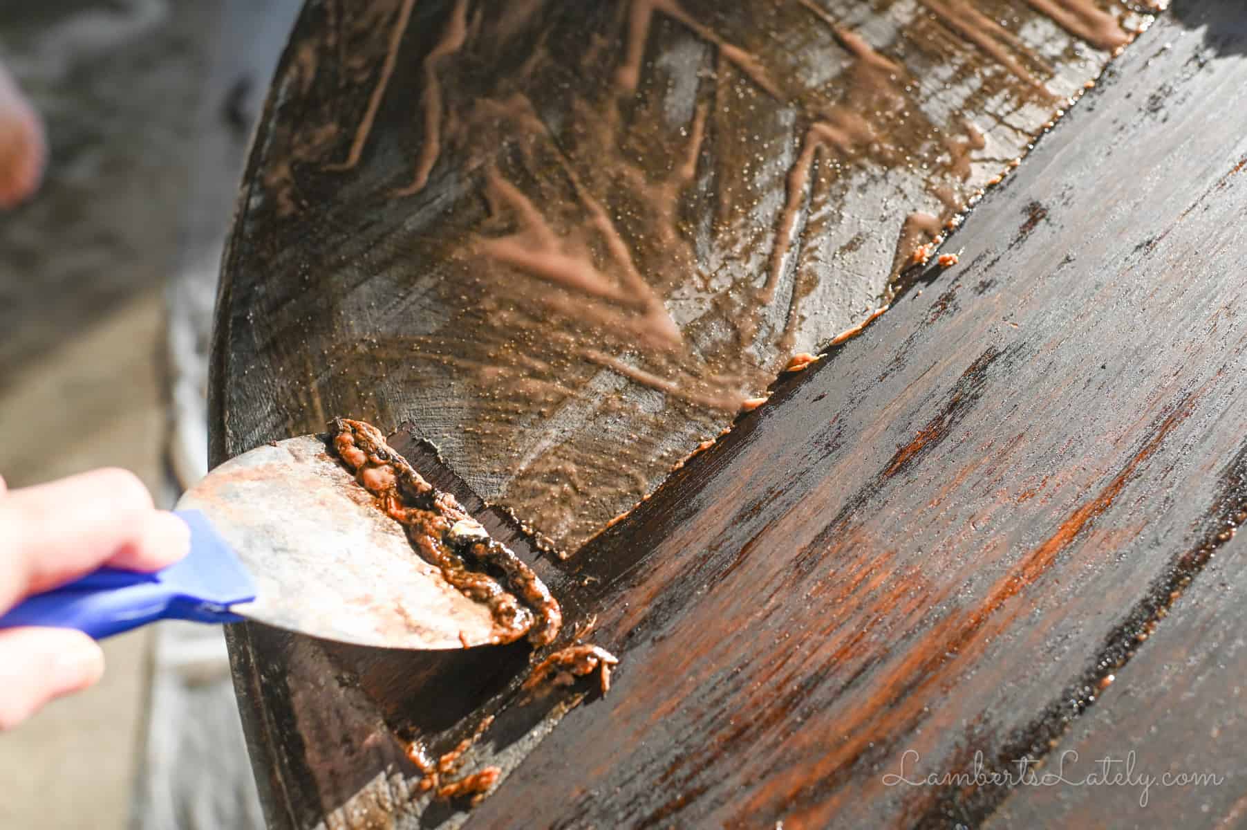 using a paint scraper to take off stripping gel and stain.