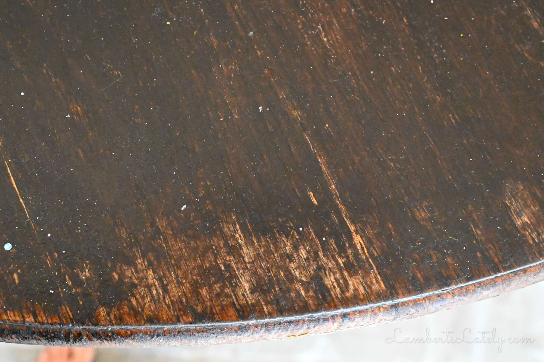 close-up of wear on a wood stained able, especially noticeable at the edges.
