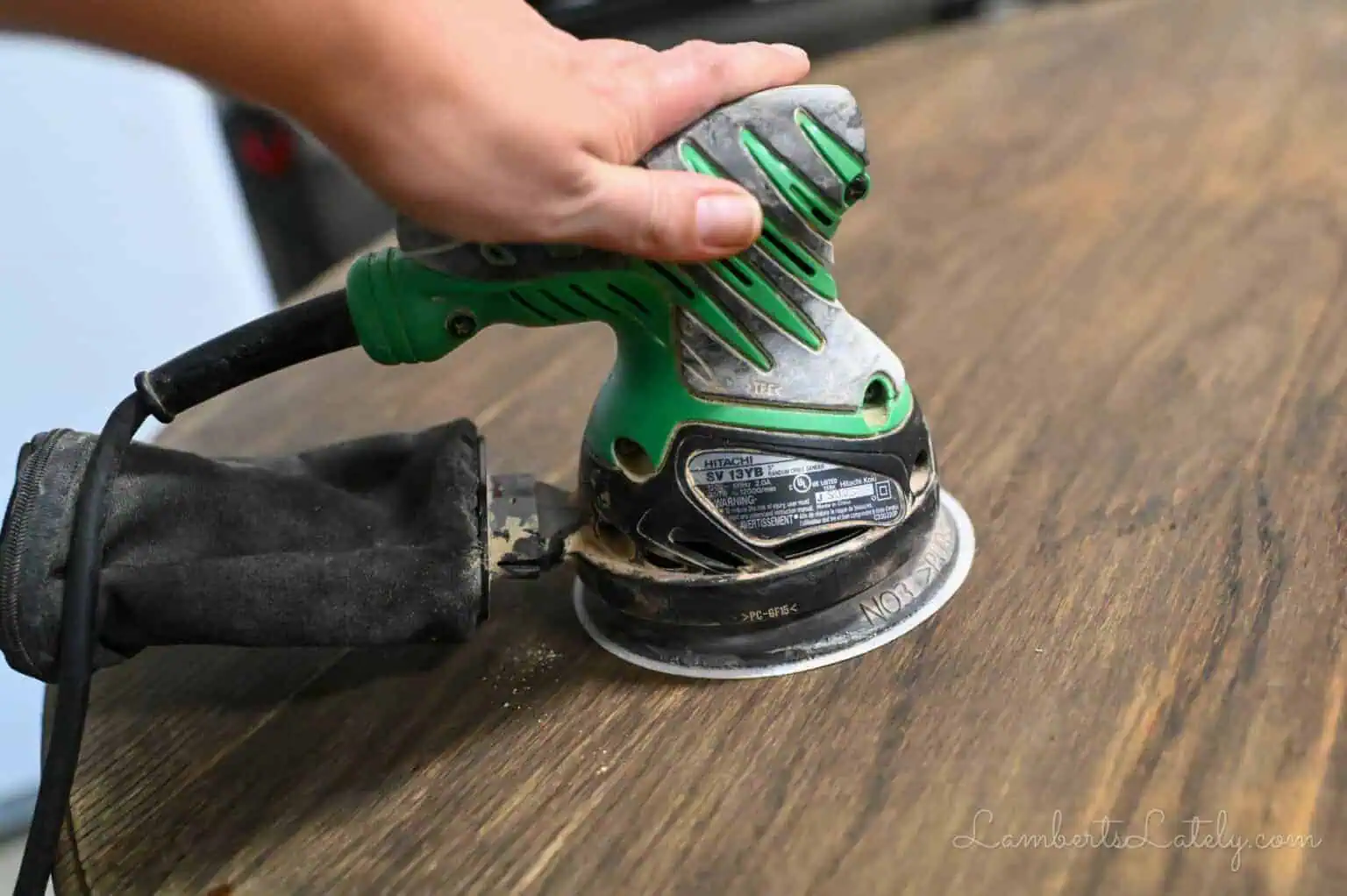 using an orbital sander on a wood table.