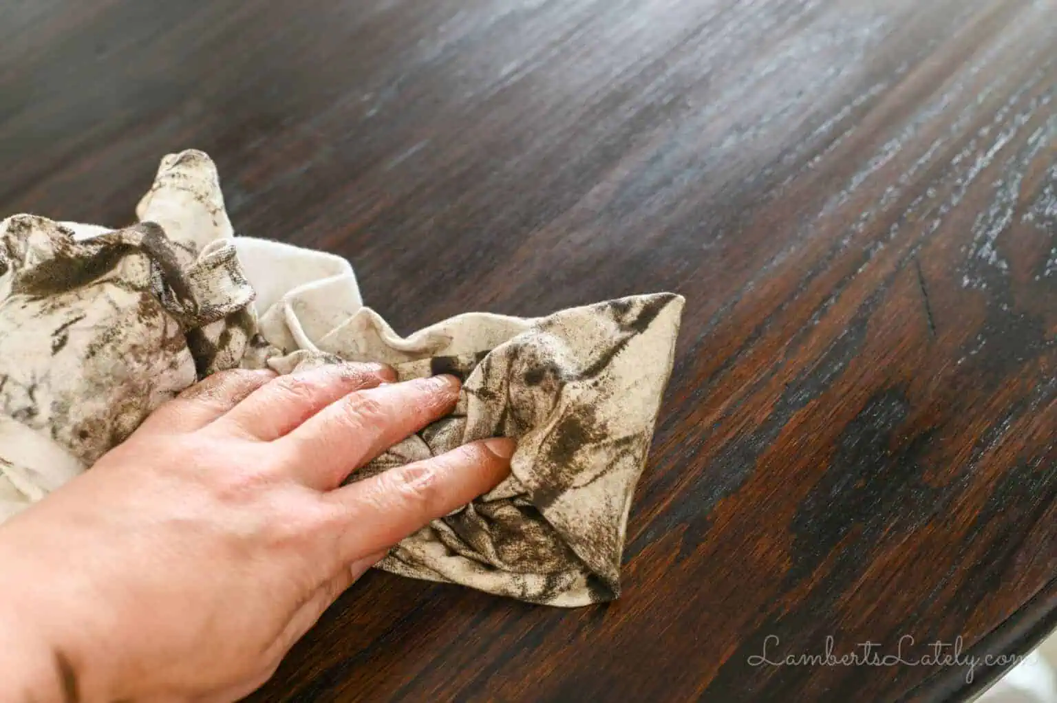 wiping stain off of a wooden table with an old t-shirt.