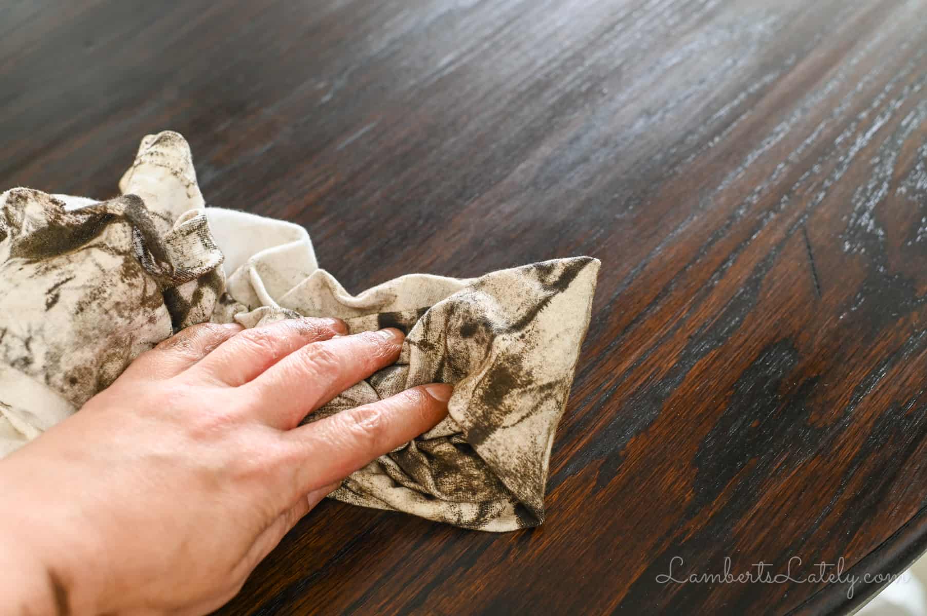 wiping stain off of a wooden table with an old t-shirt.