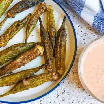 air fryer okra on a plate next to dipping sauce.