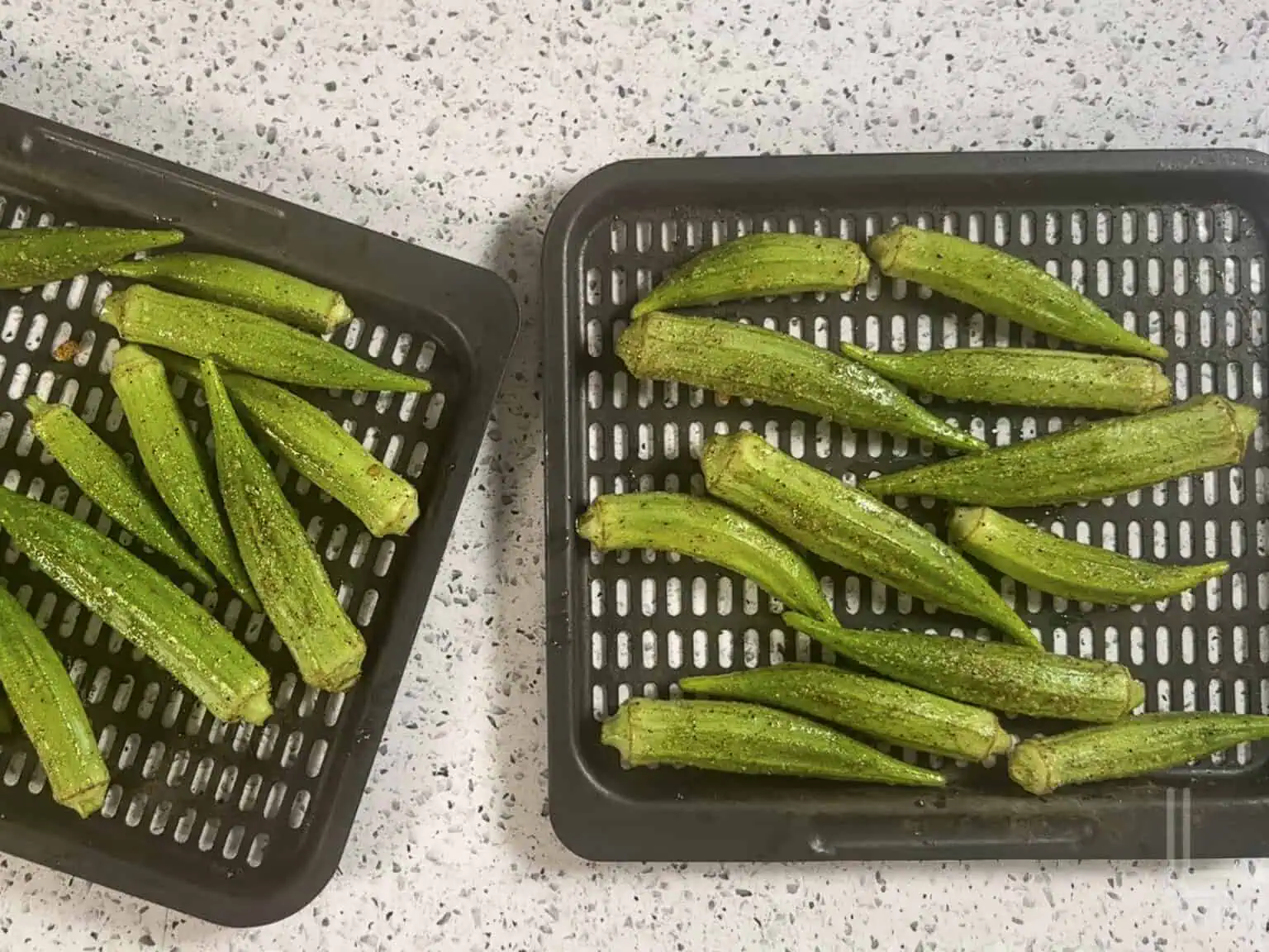the seasoned okra pods on an air fryer tray.